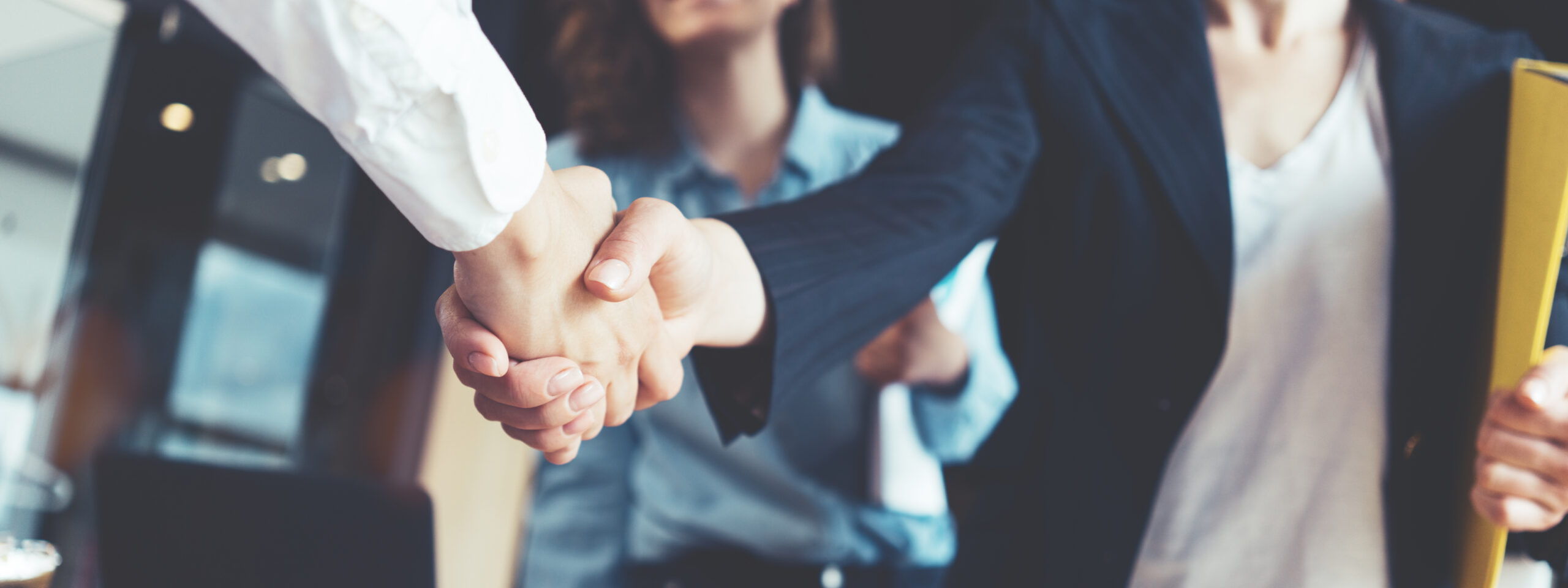 Young business people shaking hands in the office. Finishing successful meeting. Three persons. Wide screen panoramic Unternehmensnachfolge Handschlag 1