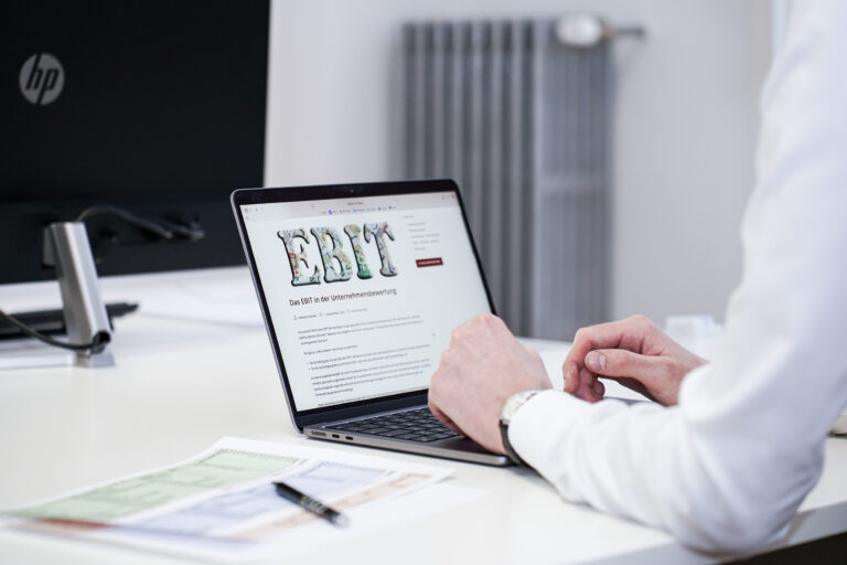 Eine Person in eine Büro schaut sich das Artikel zur EBIT-Bewertung auf dem Laptop bei Czako Partner GmbH