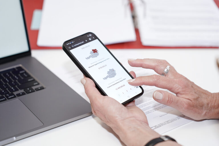 Person nutzt Smartphone zur Ansicht von Firmenangeboten mit Österreich-Karte auf der Nachfolgebörse der Czako Partner GmbH