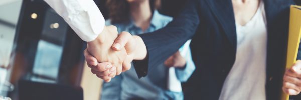 Young business people shaking hands in the office. Finishing successful meeting. Three persons. Wide screen panoramic Unternehmensnachfolge Handschlag 1